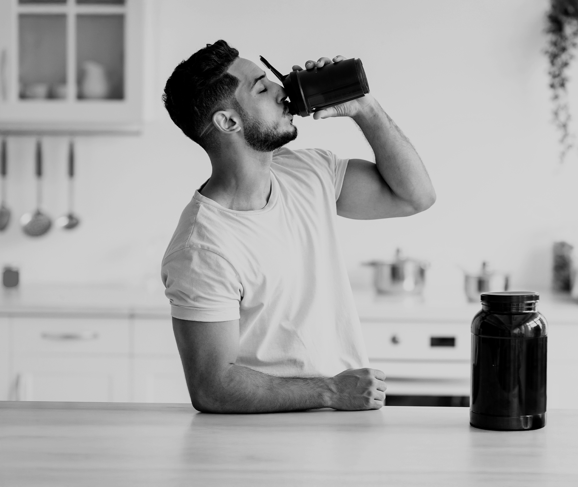 Mann trinkt aus einem Shaker in der Küche.