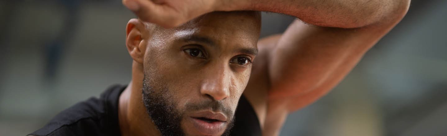 Ein Mann hält sich vor Anstrengung den Arm vor die Stirn