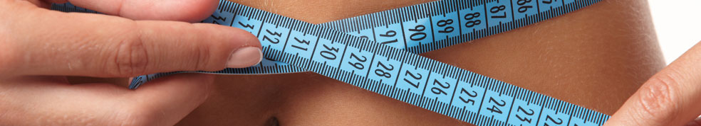 Eine Frau misst mit einem Maßband Ihren Bauchumfang