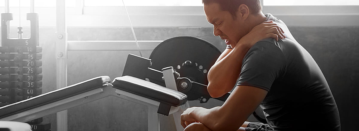 Fitness Sportler hält sich mit schmerzverzerrtem Gesicht den Nacken