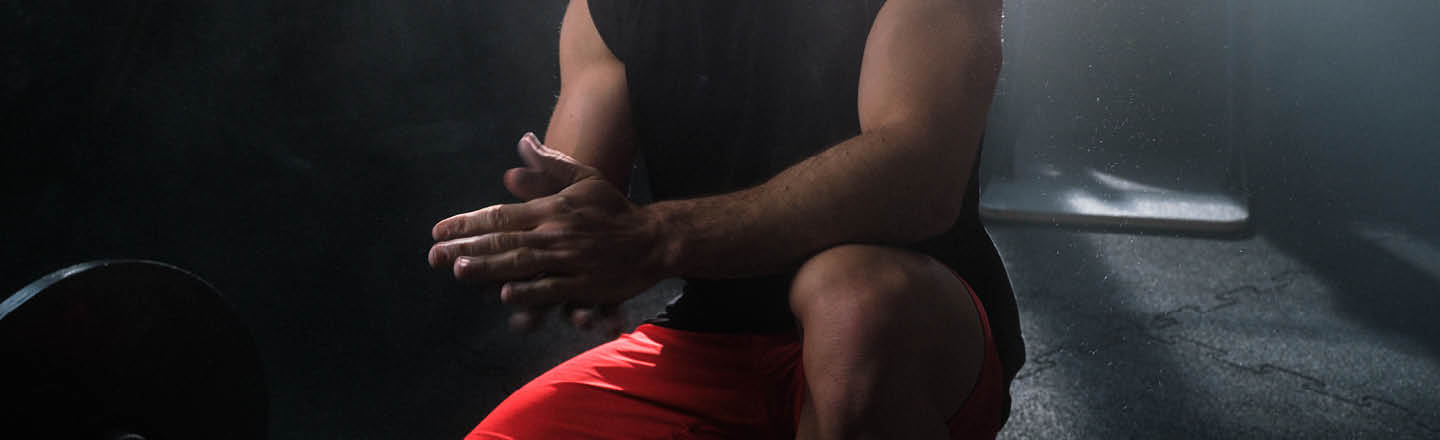 Fitness Sportler reibt in der Hocke seine Hände zusammen