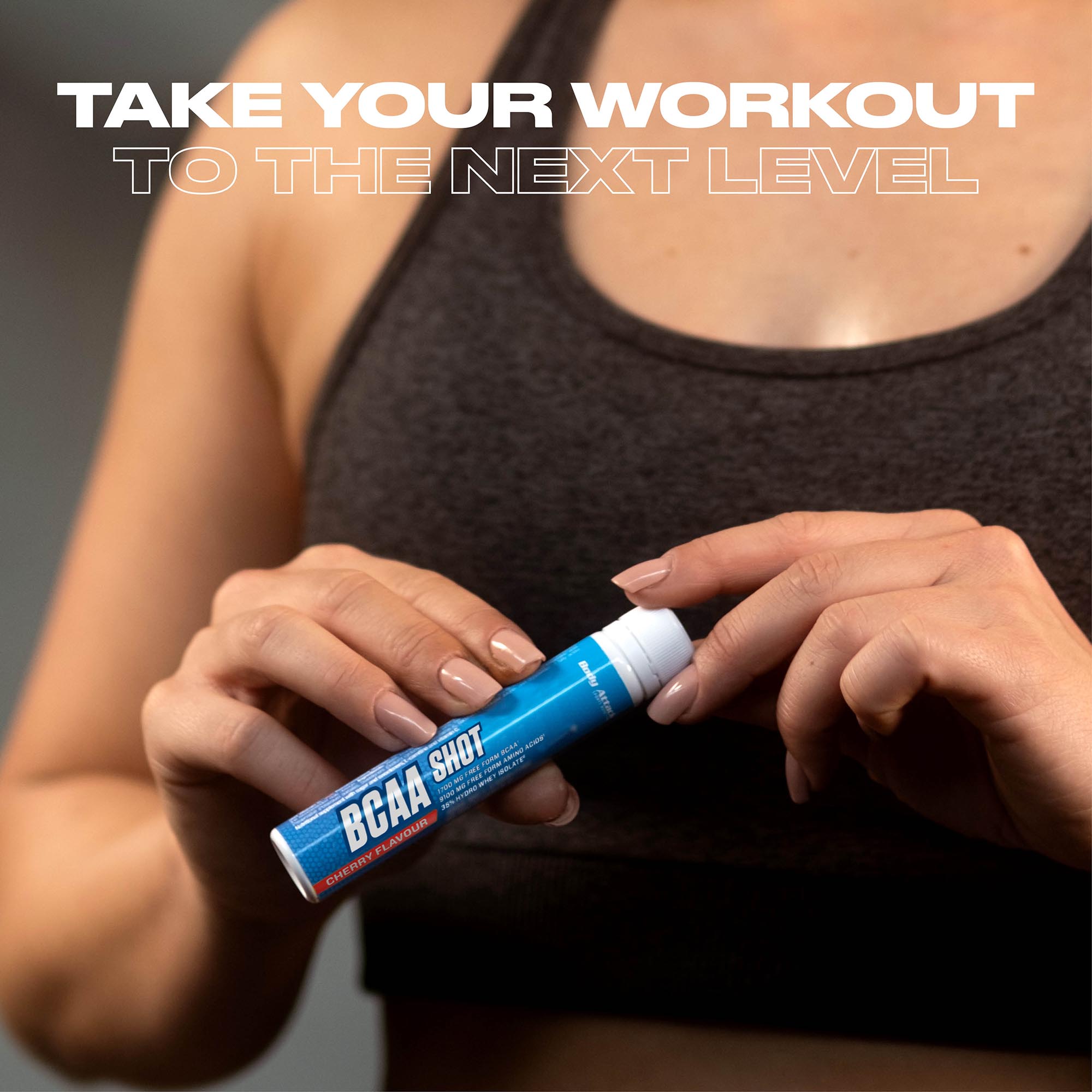 Eine Sportlerin öffnet eine BCAA Shot Ampulle