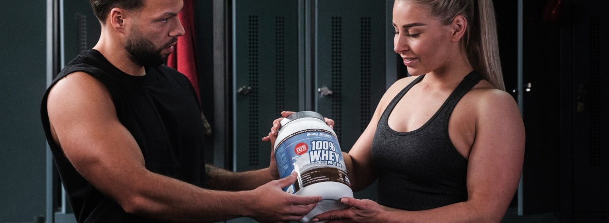 Eine Frau und ein Mann halten zusammen ein 100% Whey Protein